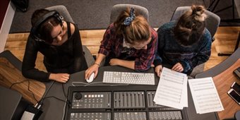 Students sat at a desk in the recording studio