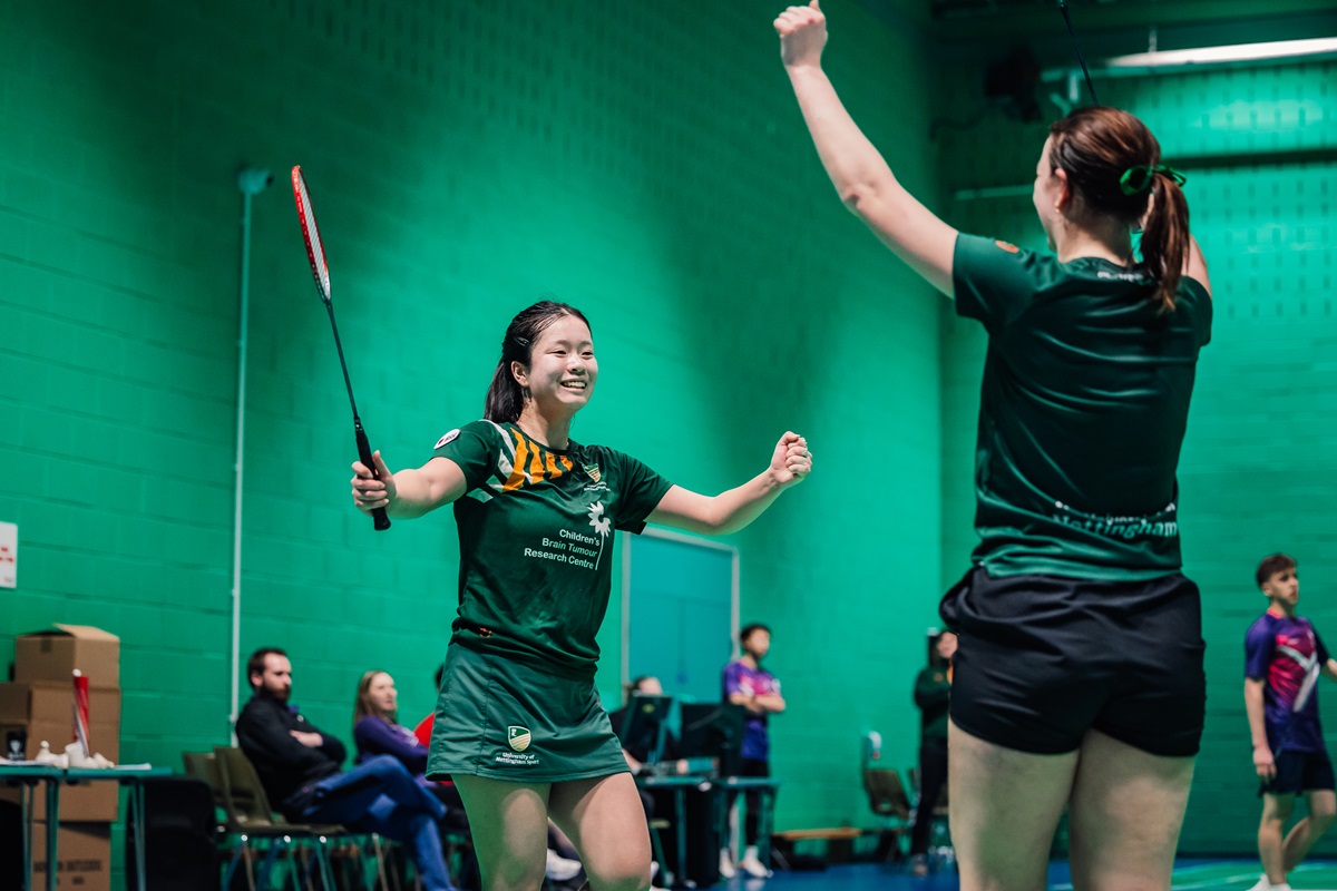 Badminton players celebrate with rackets and arms raised