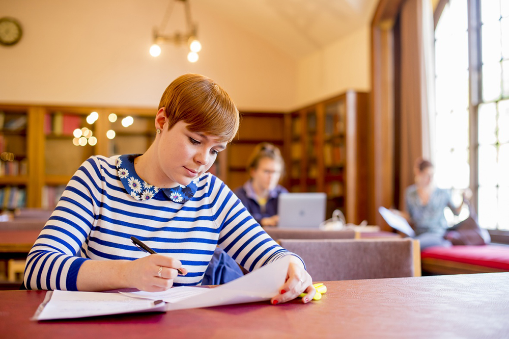 A girl sits reading in a library