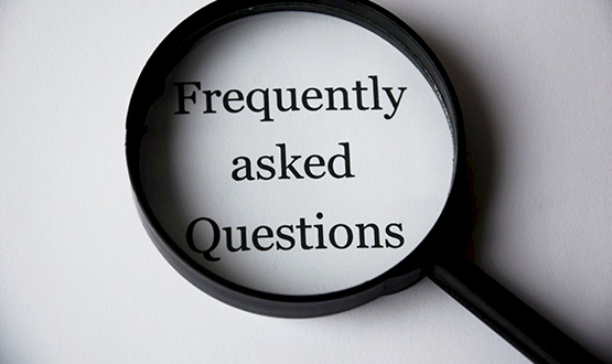 Magnifying glass with words - frequently asked questions - in middle of glass