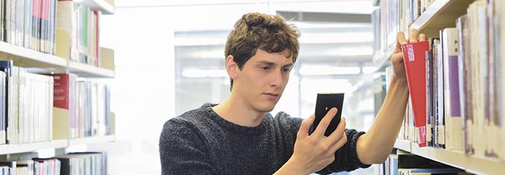 Person using a phone in the library stacks