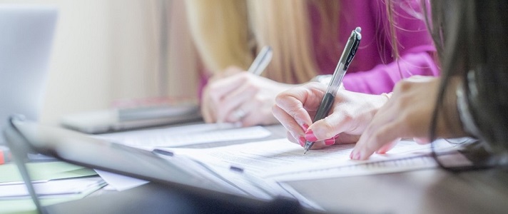 Close-up photograph of hands writing in pen in a notebook